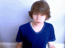 a young boy wearing a blue shirt is making a face