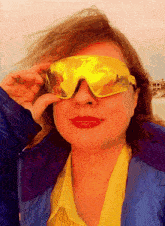 a woman wearing a blue jacket and yellow sunglasses is smiling