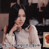 a woman with long black hair is sitting in front of a plate of food with foreign writing on it