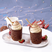two cupcakes with whipped cream and strawberries are on a plate