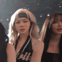 a group of women are standing next to each other on a stage . one of the women is wearing a headband .
