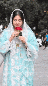 a woman in a blue dress holds a red rose