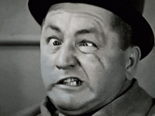 a black and white photo of a man wearing a top hat making a funny face