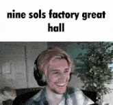 a man wearing headphones is smiling in front of a sign that says nine sol 's factory great hall