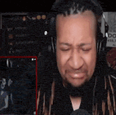 a man with dreadlocks is wearing headphones and crying while playing a video game