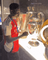 a man in a fly emirates shirt holds a trophy in his hand