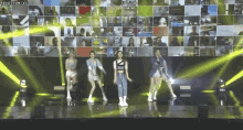 a group of young women are dancing on a stage in front of a large screen .