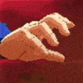 a close up of a person 's hand holding a piece of bread on a red background .