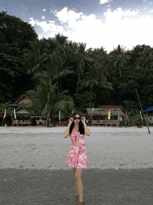 a woman in a pink dress stands on the beach