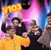 a group of men are dancing in front of a v103 sign