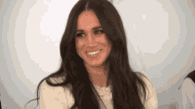a woman with long dark hair is smiling and looking at the camera