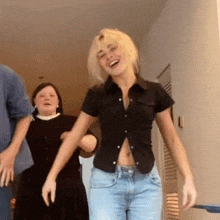 a woman in a black shirt and blue jeans is laughing while dancing