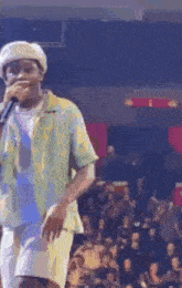 a man is singing into a microphone in front of a crowd .