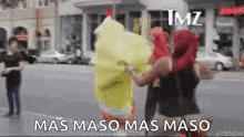 a group of people are standing on a city street holding a spongebob costume .