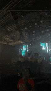 a man in a yellow shirt is standing in a dark room with the word shagarita on the bottom right