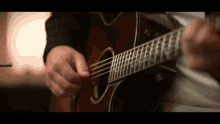 a man is playing an acoustic guitar with a white shirt on