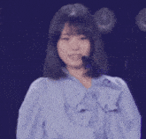 a woman wearing a blue shirt with a bow and a microphone