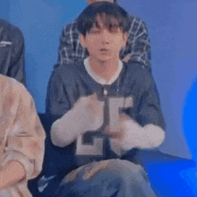 a young man is sitting in a chair with his hands on his face .
