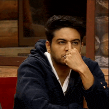 a man with a ring on his finger covering his mouth with his hand