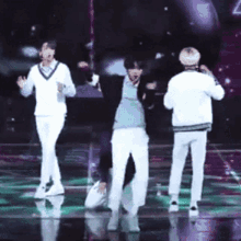 a group of people are dancing on a stage and one of them is wearing a blue shirt