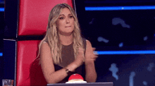 a woman sitting in a red chair applauding with her hands