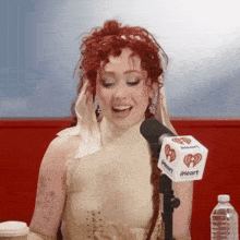 a woman with red hair is singing into a iheart radio microphone