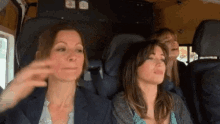 three women are sitting in the back seat of a car and one of them is making a funny face