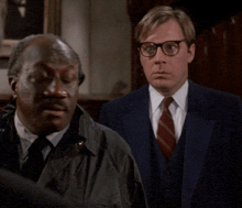 two men are standing next to each other and one has glasses on