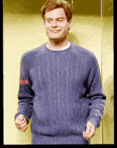 a man wearing a blue sweater is smiling and making a funny face