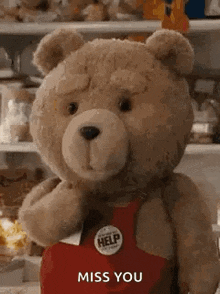 a teddy bear wearing a red apron and a badge that says `` miss you ''