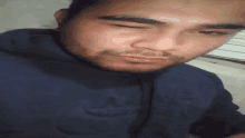 a close up of a man 's face with a beard and a blue shirt