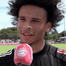 a man wearing a fc bayern munich jersey talks into a microphone