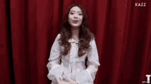 a woman is standing in front of a red curtain .