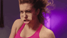 a woman in a pink tank top making a face
