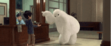a boy is standing next to a stuffed bear in a room .