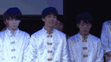 a group of young men are standing in a line wearing white jackets with gold buttons