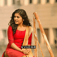 a woman in a red dress is sitting on a wooden railing with kvvcsr written on the bottom