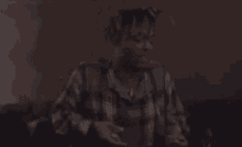a man in a plaid shirt is sitting on a couch with his hands in the air .
