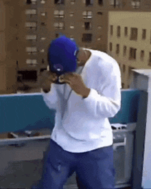 a man wearing a white shirt and blue hat is dancing