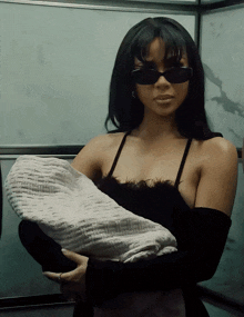 a woman wearing sunglasses is holding a blanket