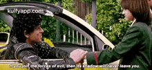 a man is shaking hands with a woman in a car while another man looks on .