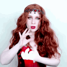 a woman with long red hair is wearing a red corset and a headband