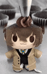 a stuffed toy is being decorated with chocolate frosting in front of cupcakes