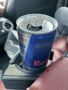 a can of red bull is sitting in a car cup holder