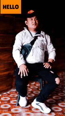 a man is sitting on a chair with a hello sign behind him