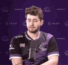 a man wearing a purple shirt that says twitch on the collar