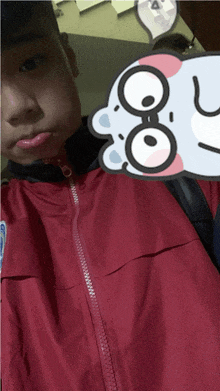 a man in a red jacket is taking a selfie with a sticker that says ' a ' on it