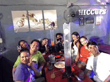 a group of people posing for a picture in front of a wall that says hiccups