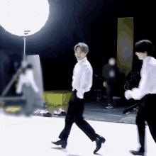 a man in a white shirt is walking in front of a light which says ' panasonic ' on it