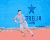 a man is playing tennis in front of a sign for estrella damm